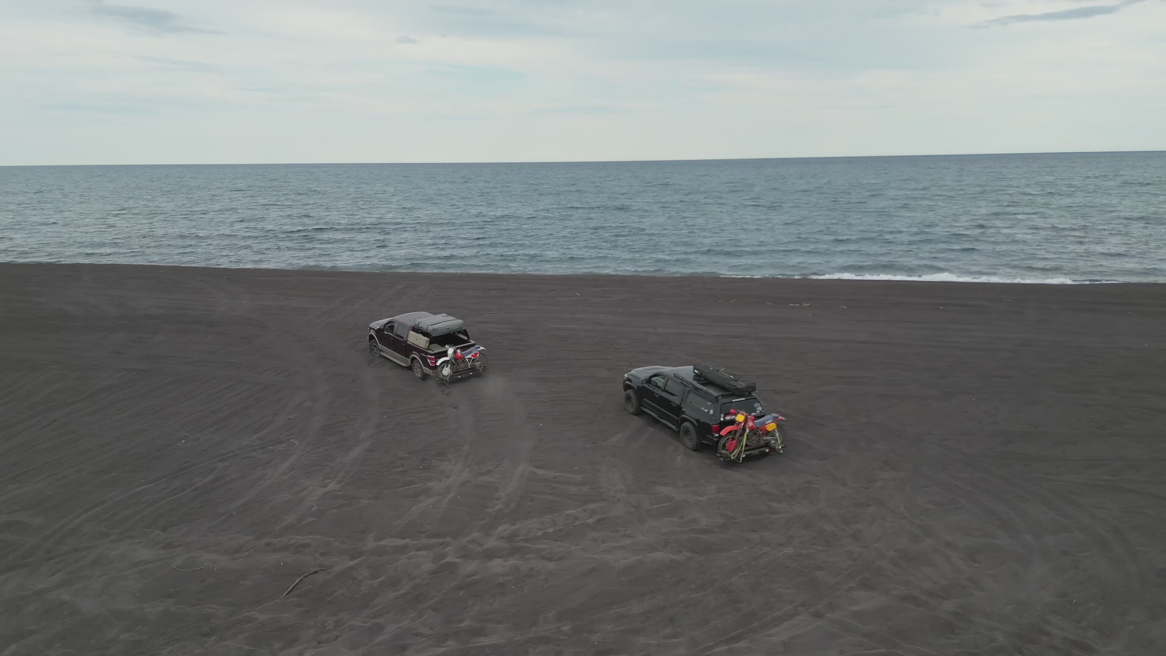 Load video: Trucks and dirtbikes riding along the coastline of lake superior